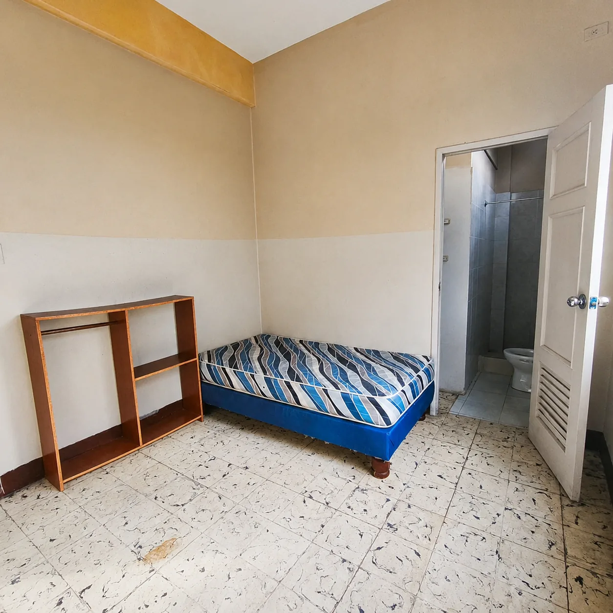 Habitación con cama individual y acceso a baño